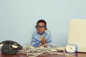 Young Boy IT Professional Smiles at Computer with Wire